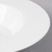 A close-up of a wide rimmed white bone china pasta plate.