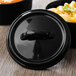 A black matte porcelain lid with a handle on a black Bon Chef cocotte.