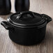 A matte black Bon Chef porcelain cocotte lid on a black pot.