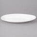 A close up of a white Bon Chef slanted oval porcelain plate with a fork.