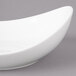 A white Bon Chef porcelain pasta bowl with a curved edge on a gray background.