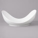 A white Bon Chef pasta bowl with a curved shape on a gray background.
