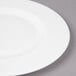 A close-up of a Bon Chef white bone china dinner plate with a wide rim.