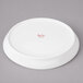 A white Bon Chef porcelain plate with a red rim.