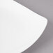 A close-up of a white Bon Chef porcelain salad plate with a curved edge.