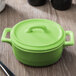 A lime green Bon Chef oval cocotte lid on a table.
