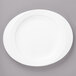 A white Bon Chef porcelain oval plate with a rim on a gray surface.