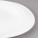 A close-up of a Bon Chef white porcelain oval dinner plate with a curved edge.