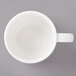 A white Bon Chef porcelain espresso cup with a circle in the middle on a white saucer.