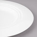 A close-up of a Bon Chef white porcelain round dinner plate with a circular rim.