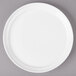 A white porcelain plate with a white rim on a gray surface.
