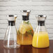 A GET Silhouette glass decanter filled with orange juice and lemon slices on a counter.