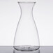 A clear glass decanter with a stainless steel lid on a table.