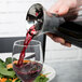A person using a GET Silhouette glass decanter to pour red wine into a glass.