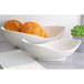 Two 10 Strawberry Street white porcelain canoe bowls filled with bread on a table.