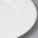 A close up of a Bon Chef white bone china charger plate with a white rim.