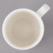 A white Bon Chef porcelain cup with a circle in it containing a small amount of liquid.