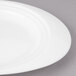 A close up of a white Bon Chef porcelain oval salad plate with a curved rim.