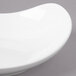 A white Bon Chef porcelain pasta bowl with a curved edge on a gray surface.