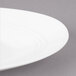 A close-up of a white Bon Chef slanted oval porcelain plate with a curved rim.