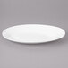 A white Bon Chef porcelain oval plate with a rim on a gray surface.