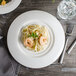 A white porcelain bowl filled with shrimp pasta.