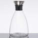 A clear glass decanter with a stainless steel lid.