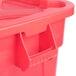 A close up of a red Rubbermaid BRUTE trash container with a snap-lock lid.
