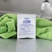 A white Noble Chemical powdered beer glass cleaner packet on a counter with a green towel.