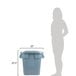 A woman standing next to a Rubbermaid BRUTE 28 gallon grey square trash can with a lid.