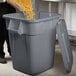 A man pouring pasta into a Rubbermaid BRUTE trash can.