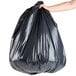 A person's arm holding a black Berry trash bag.