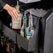 A person pouring liquor into a Cambro portable bar with a 5-bottle speed rail.