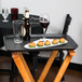 A Cambro black non-skid serving tray with food and wine on a table.