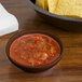 A brown GET Salsa Dish filled with salsa on a table with chips.