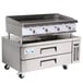 A stainless steel countertop griddle with a refrigerated base with drawers.