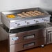 A Cooking Performance Group gas countertop griddle with food cooking on it.