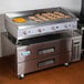 A large stainless steel Cooking Performance Group gas countertop griddle with food on it.