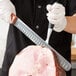 A person in gloves using a Mercer Culinary Praxis slicer knife to cut a ham.