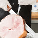 A person using a Mercer Culinary Praxis slicer knife to cut ham on a table.