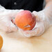 A person using a Mercer Culinary Praxis paring knife to peel an apple.