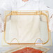 A chef holding a clear plastic container of food with a Carlisle amber high heat hinged lid.