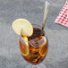 A glass of iced tea with lemon and a stainless steel heavy weight iced tea spoon.