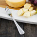 A Walco stainless steel cocktail fork next to cheese and fruit.