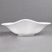 A white Villeroy & Boch porcelain bowl with a curved edge on a gray surface.