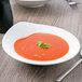 A white Villeroy & Boch porcelain deep bowl filled with tomato soup garnished with a leaf.