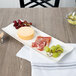 A Villeroy & Boch white porcelain rectangular platter with cheese and grapes on it.