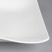 A close up of a white Villeroy & Boch porcelain square plate with a curved edge.