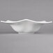 A white Villeroy & Boch porcelain bowl with a curved edge on a gray background.