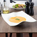 A Villeroy & Boch white porcelain deep bowl filled with soup on a table.